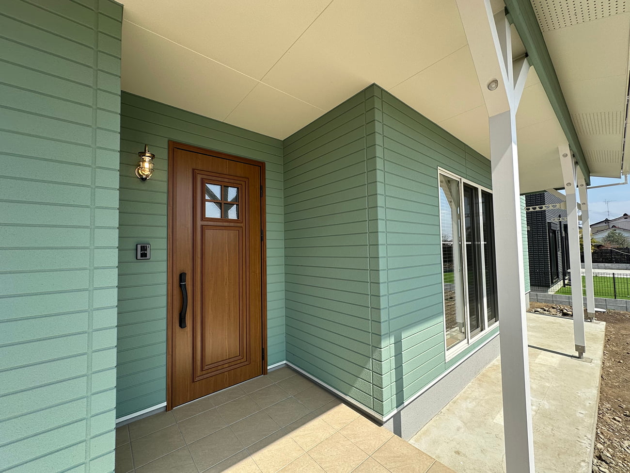 青空に映えるグリーンの外観とカバードポーチ